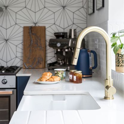 blue kitchen with white worktops and sink with gold tap