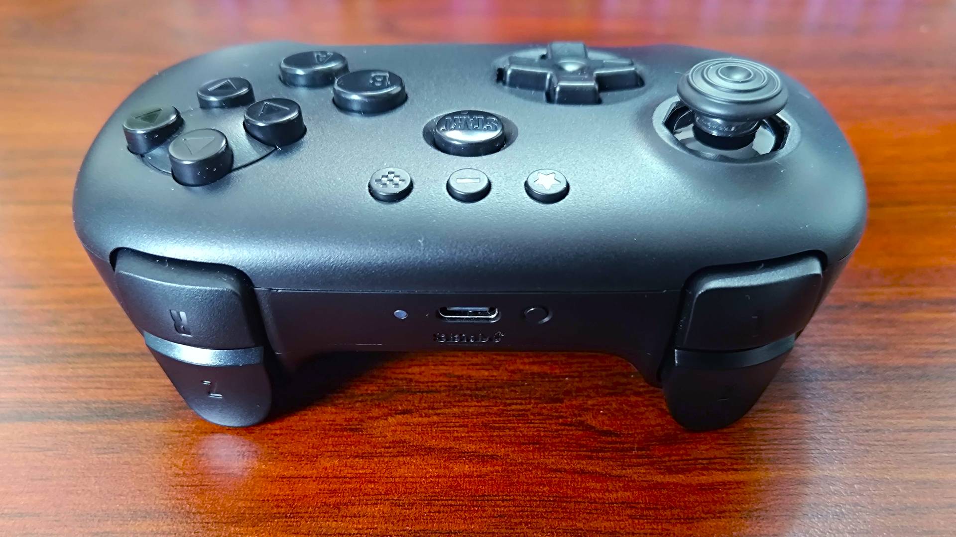 Top view 8Bitdo N64 Bluetooth controller triggers and USB-C port on woodgrain surface.