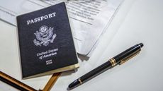 An American passport sitting on top of paperwork next to a pen.