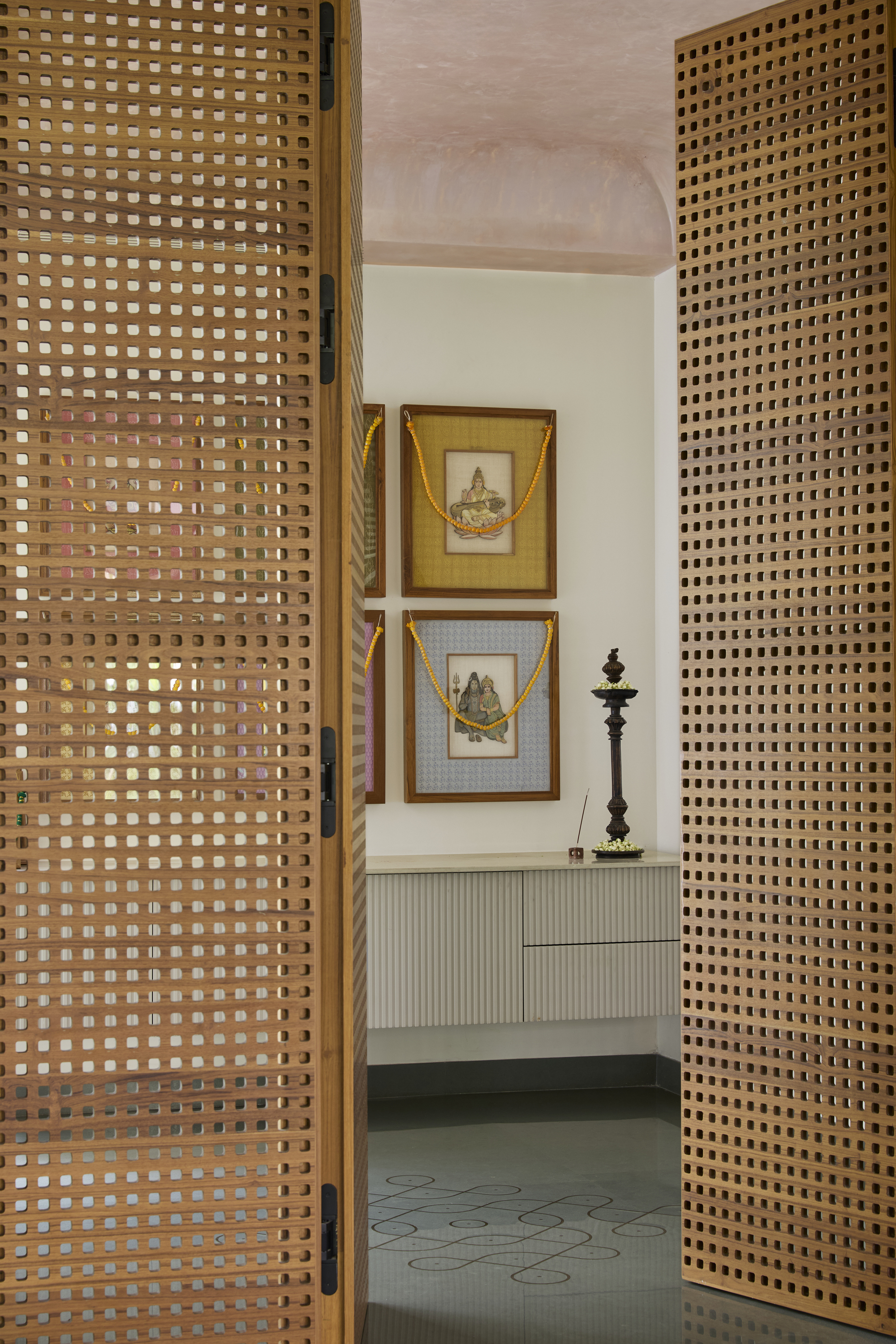 entryway with perforated timber doors, pink plaster ceiling, fluted vanity, artwork hanging on walls, and tiled floor
