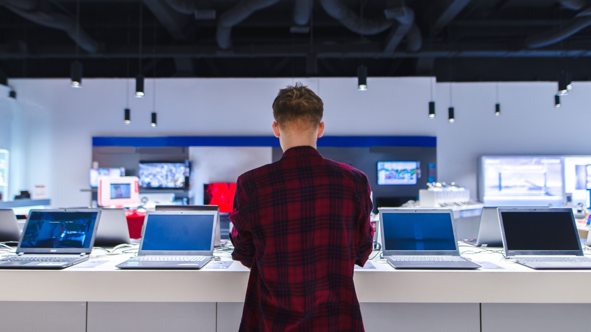 man standing in front of several laptops