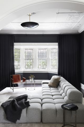 A white living room with dark, black out curtains