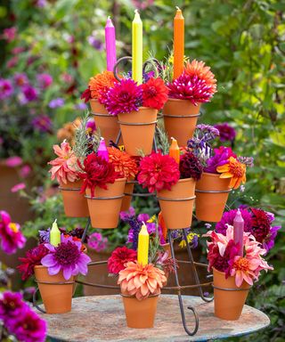 A tiered candle display with pots and dahlias