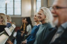 An older couple and their adult daughter smile in the pews at a church service.