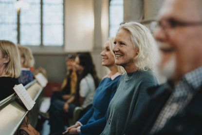 An older couple and their adult daughter smile in the pews at a church service.