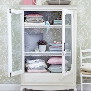 white armoire with cushions and throw