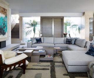 Modern living room with L-shaped grey couch and tiered coffee table holding books and trinkets