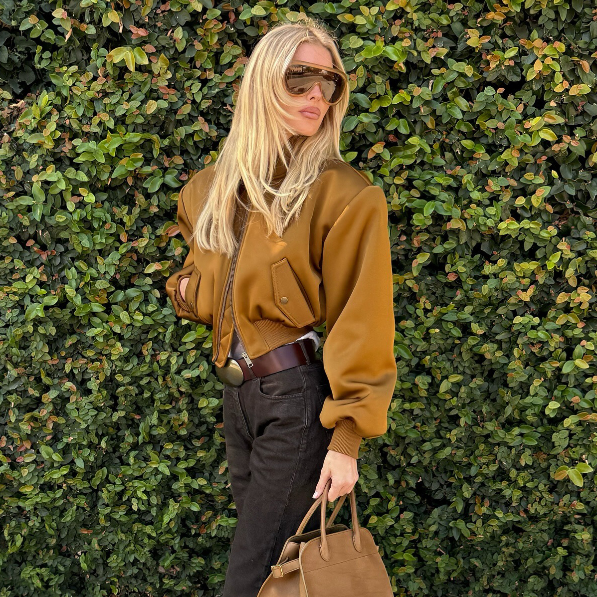 Elsa Hosk wearing a tan bomber jacket, brown jeans, and olive green shoes