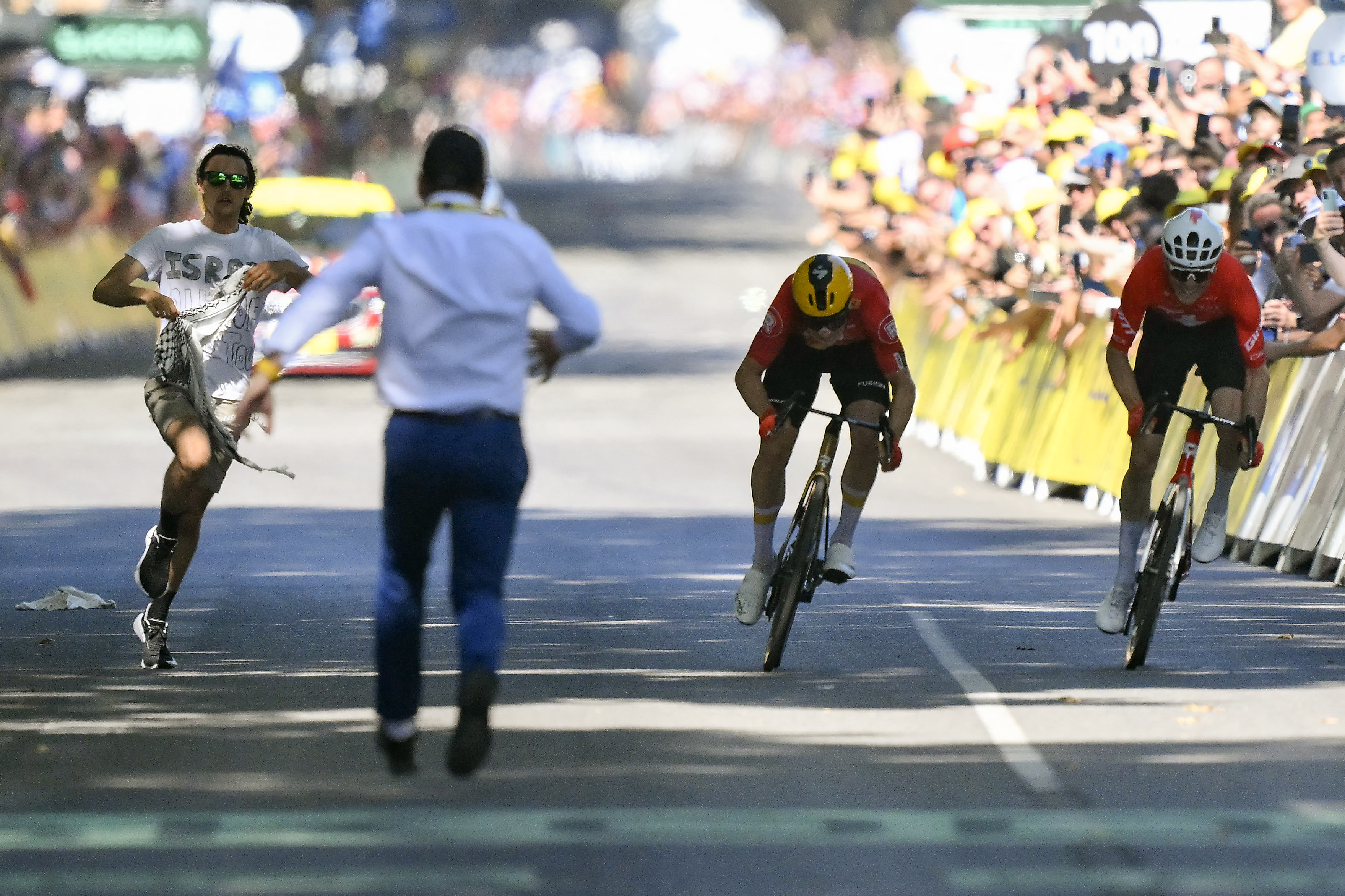 Mauro Schmid and Jonas Abrahamsen sprint for victory at the Tour de France as a protestor runs on the road