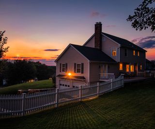 A security light shining on a colonial home at night