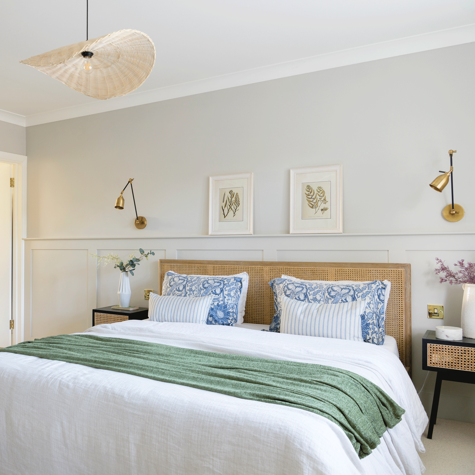 White room with rattan headboard and gold wall lamps