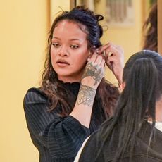 Rihanna wears a denim Levi's jumpsuit with Puma Speedcat Sneakers.