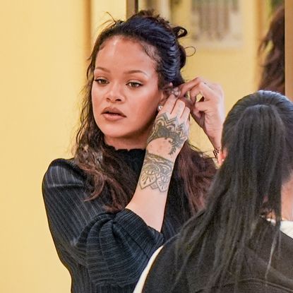 Rihanna wears a denim Levi's jumpsuit with Puma Speedcat Sneakers.