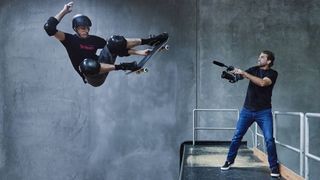 Tony Hawk performing a trick on a skateboard while being filmed by director Sam Jones 