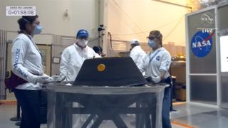 scientists in white look at the OSIRIS-REx asteroid sample return capsule
