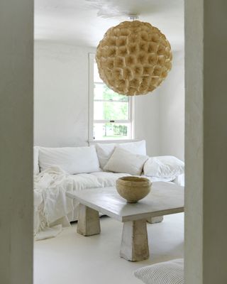 Living room with pale concrete floor, white walls and white furniture