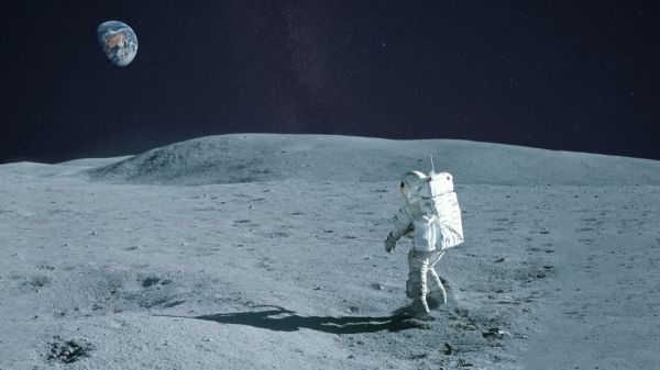 An astronaut walking across the lunar surface with Earth on the horizon.