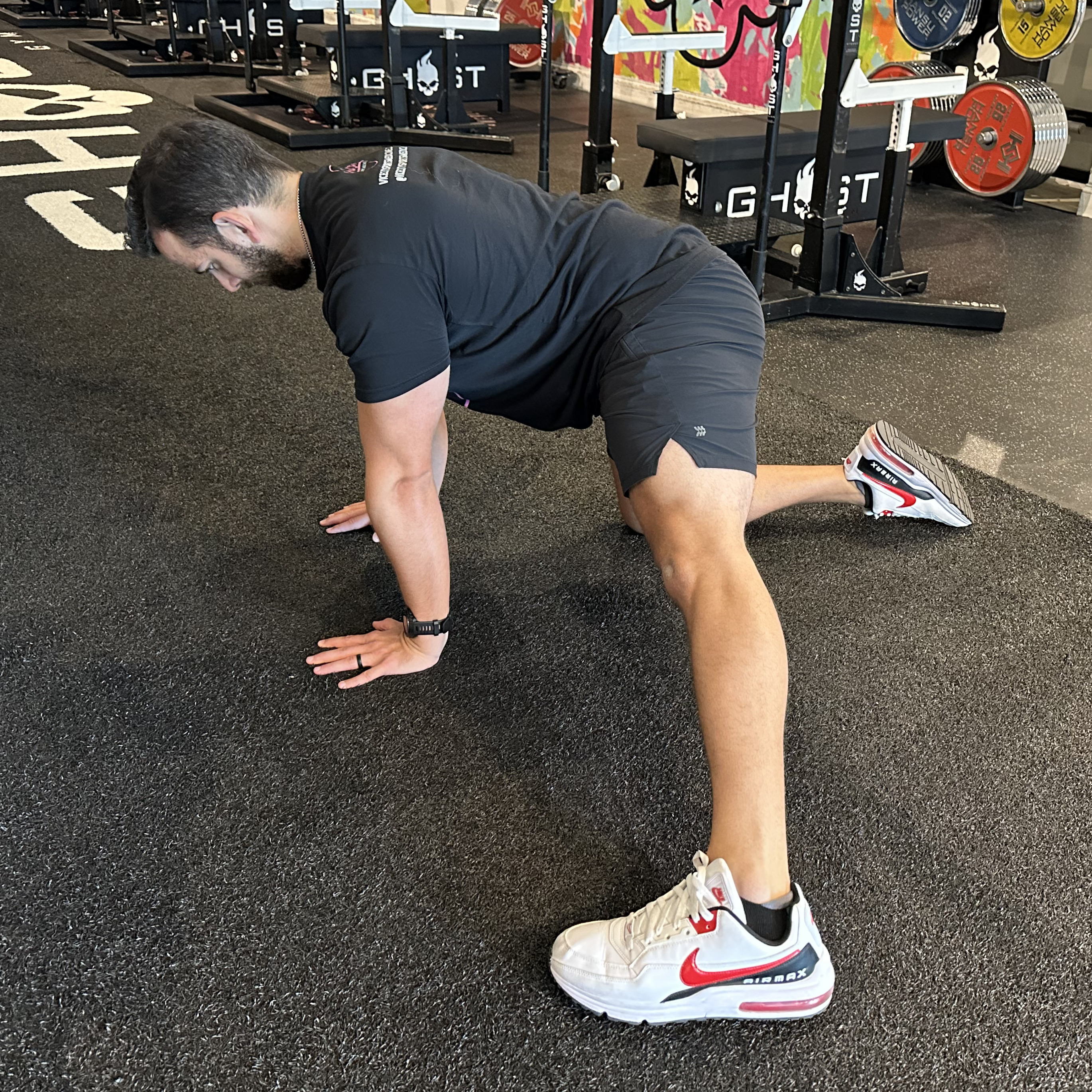 A Vice City Sports Medicine performs and adductor rockback in a gym setting. He is on his hands and right knee, with his left leg positioned straight out to the side. 