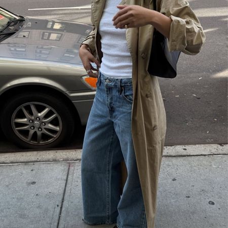 A woman wearing baggy jeans, a white vest and a stylish trench coat in New York