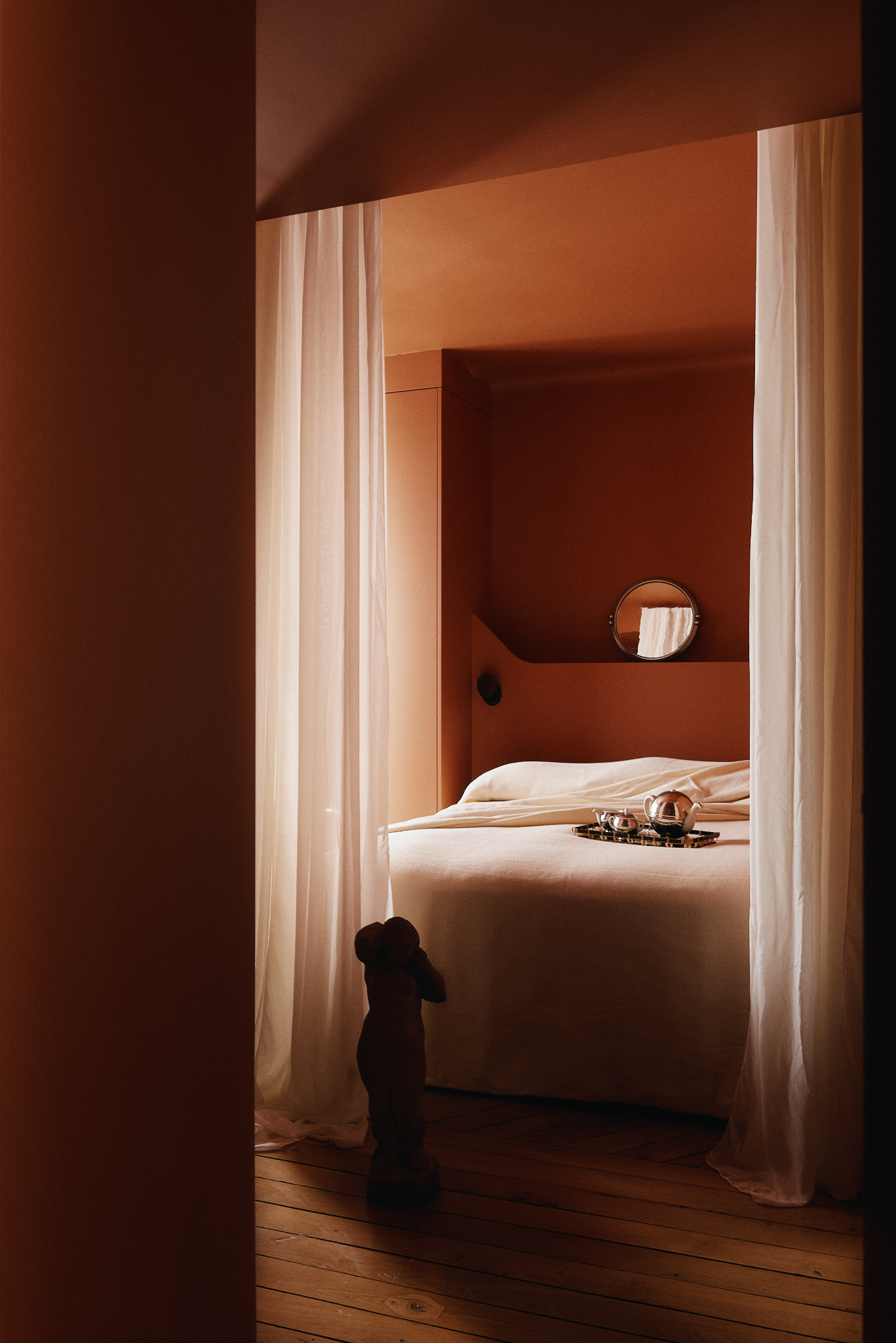 Image of an orange-drenched bedroom with sheer curtains for the doors.