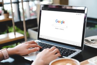 A person using a laptop to access the Google home screen