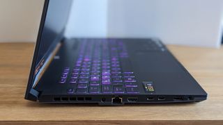 A black ASUS TUF Gaming A15 laptop on a wooden table