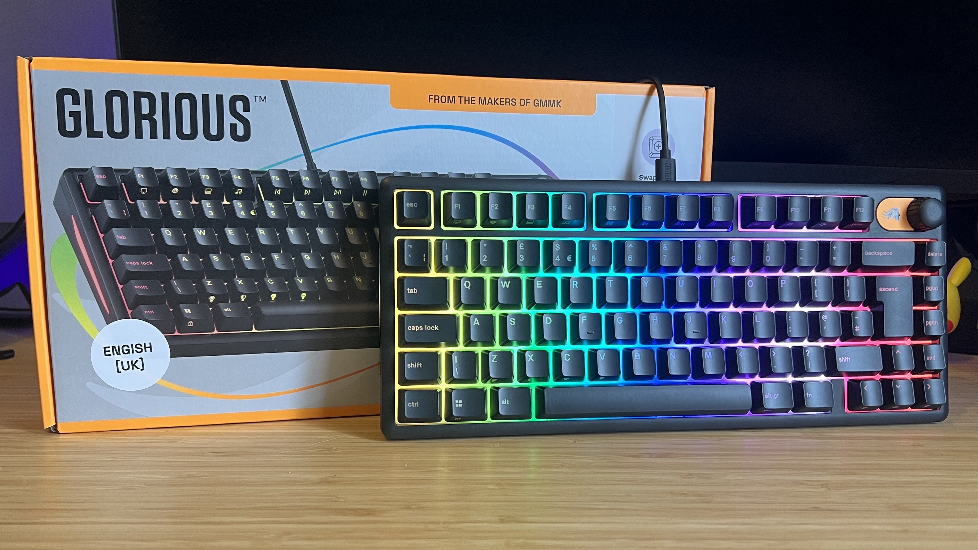 Glorious GMBK 75% gaming keyboard sitting against packaging on a wooden desk