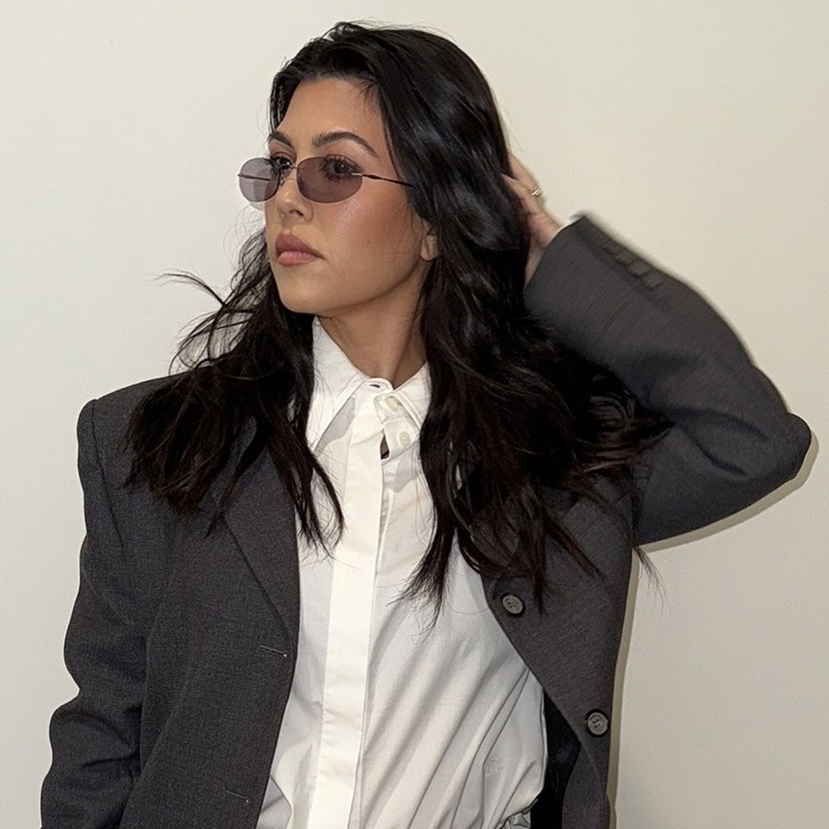 Kourtney Kardashian wears a white shirt and a gray blazer