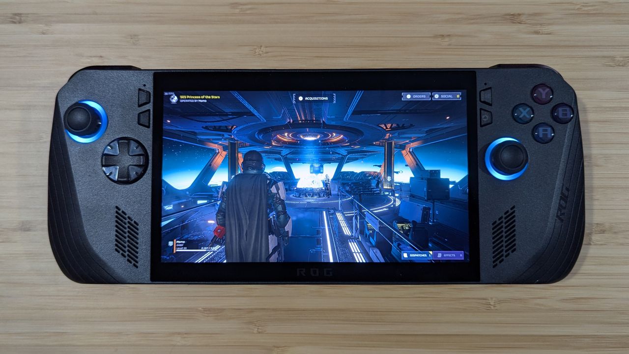 Asus ROG Ally X on a wooden table with Helldivers 2 playing on screen.