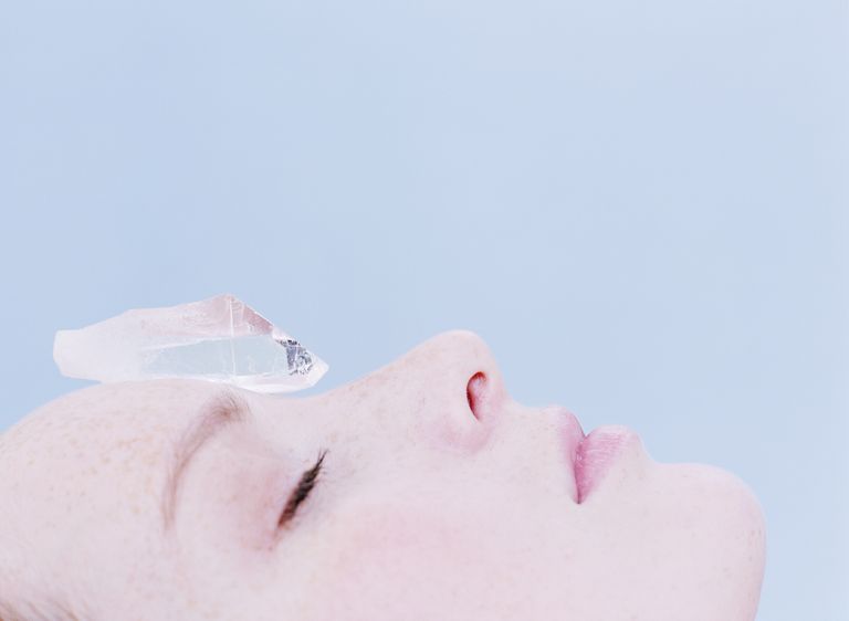 Woman with crystal on forehead, eyes closed, close-up, crystals to help sleep