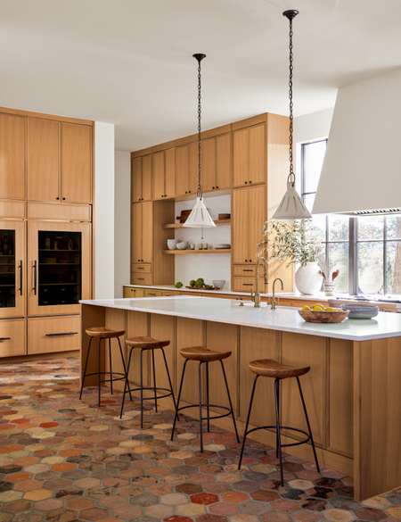 Warm, modern kitchen featuring custom wooden cabinetry, industrial-style pendant lights, and hexagonal Hapsburg terracotta tiles from Paris Ceramics