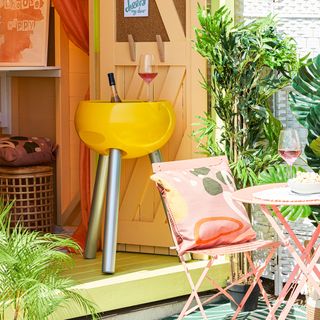 orange painted beach hut with yellow drinks cooler and outdoor table and chairs
