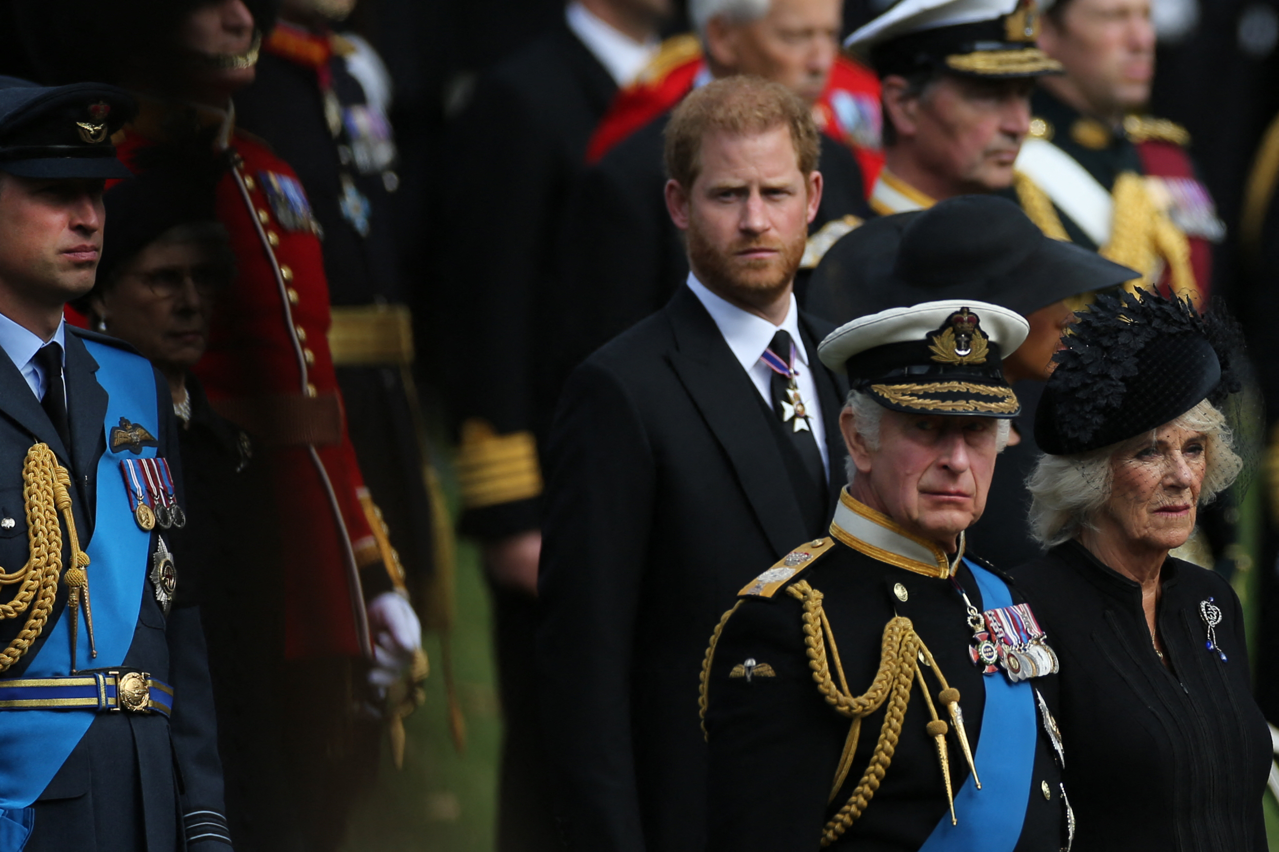 King Charles in a military uniform standing in front of Prince Harry at Queen Elizabeth's funeral