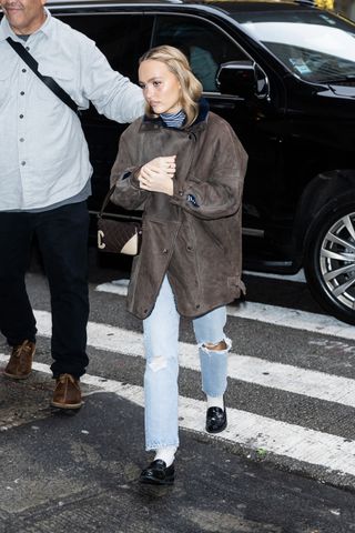 Lily-Rose Depp is seen in Midtown on December 17, 2024 in New York City wearing a leather barn coat, Levi's jeans, socks, and loafers.