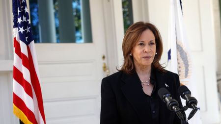 vice president kamala harris standing at a podium in front of an american flag