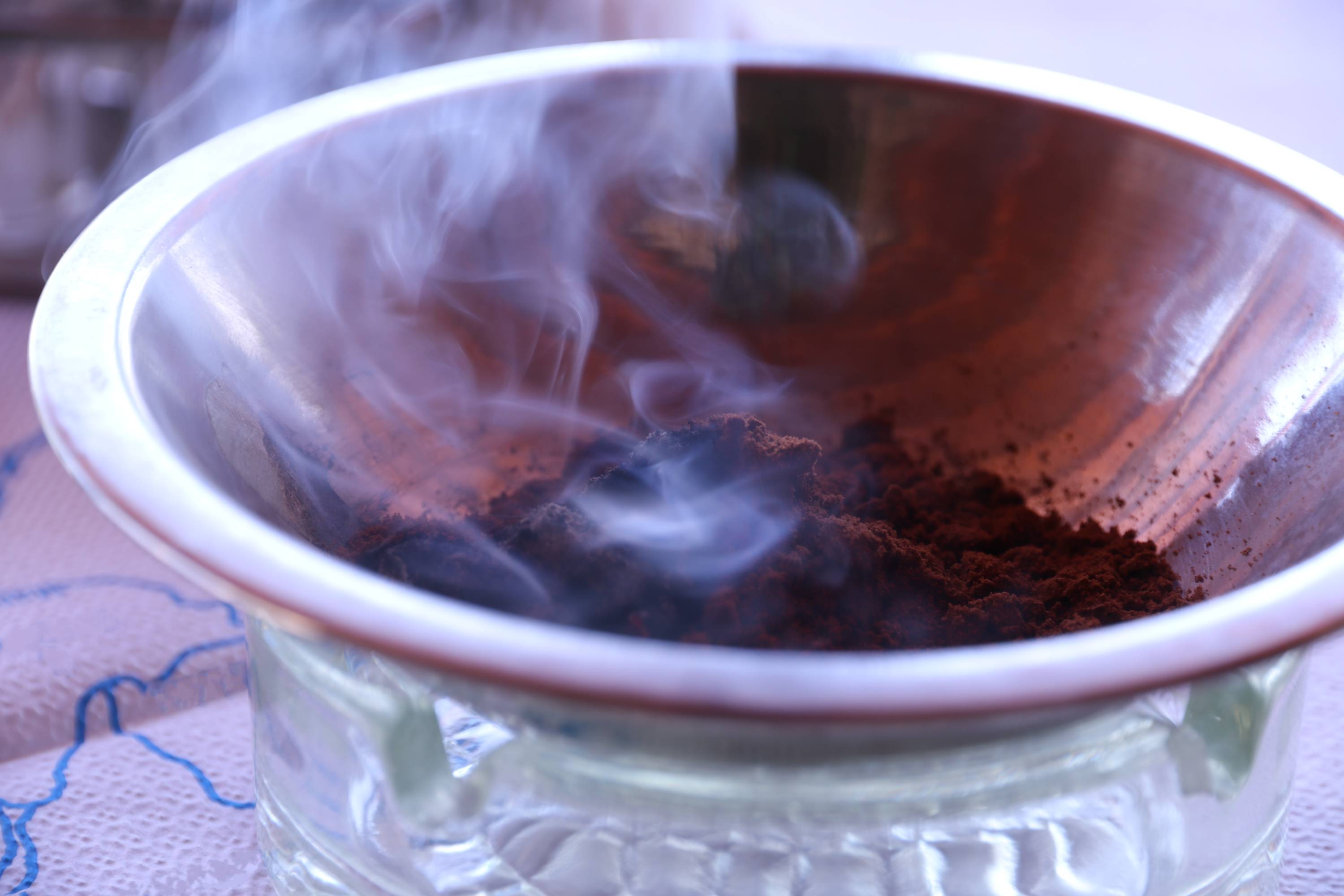 Smoke rising from a metal bowl of coffee grounds