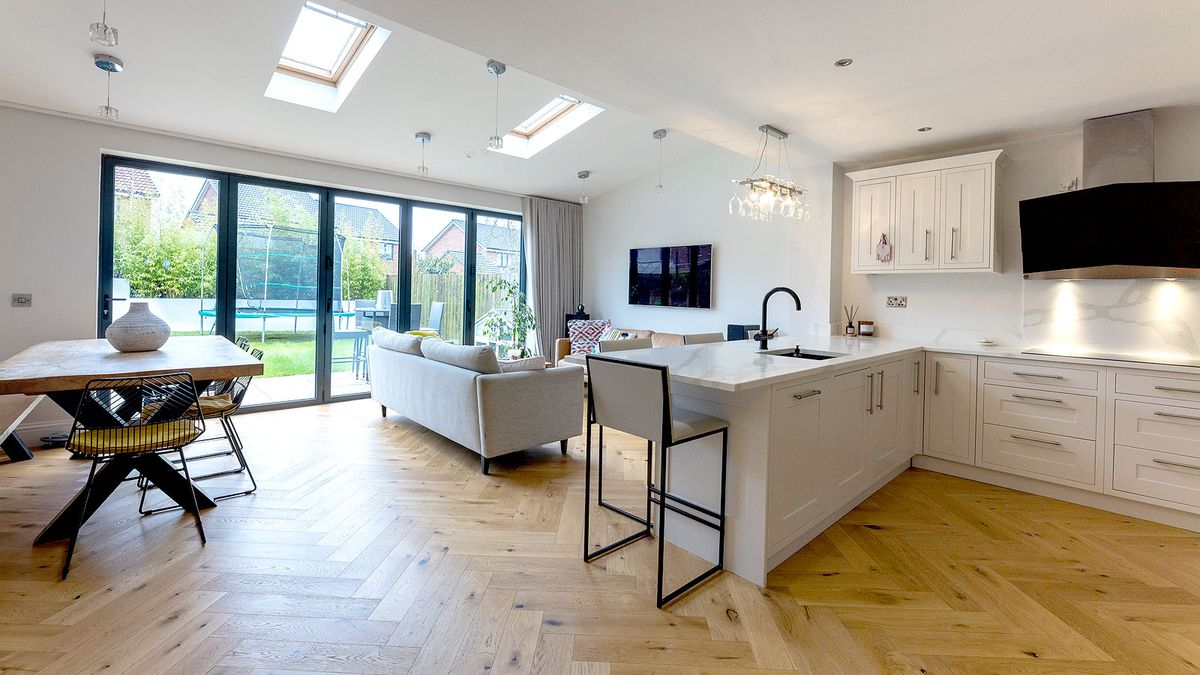 White contemporary kitchen with bifold doors and light wooden floor