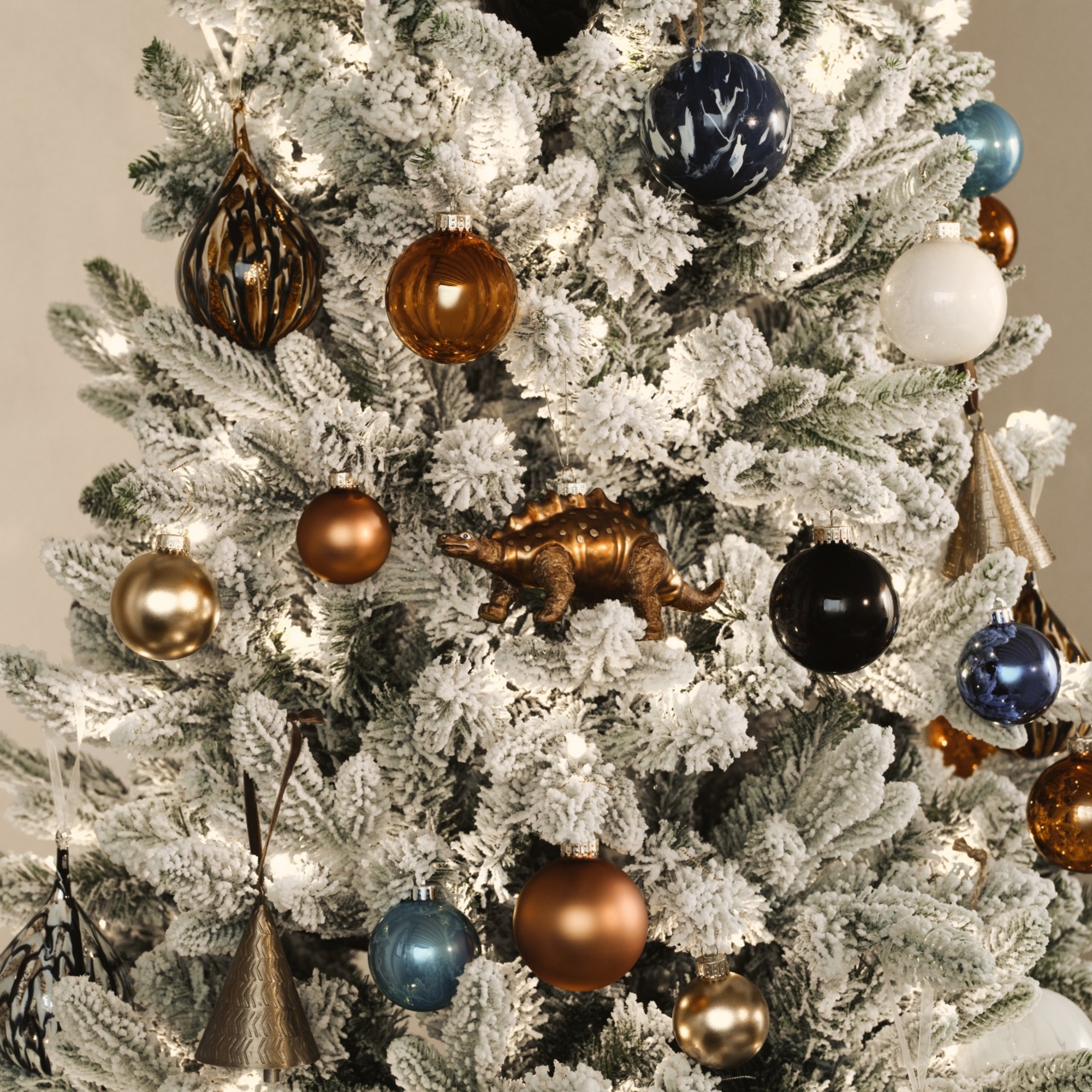 A Frosted Christmas tree decorated with Christmas decorations from the John Lewis Ancient Wonders range