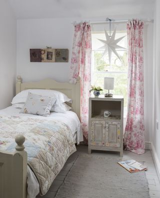 Children's bedroom with pink curtains and books on floor