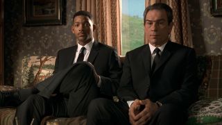 Will Smith and Tommy Lee Jones patiently sitting on a couch, listening to a story in Men in Black.