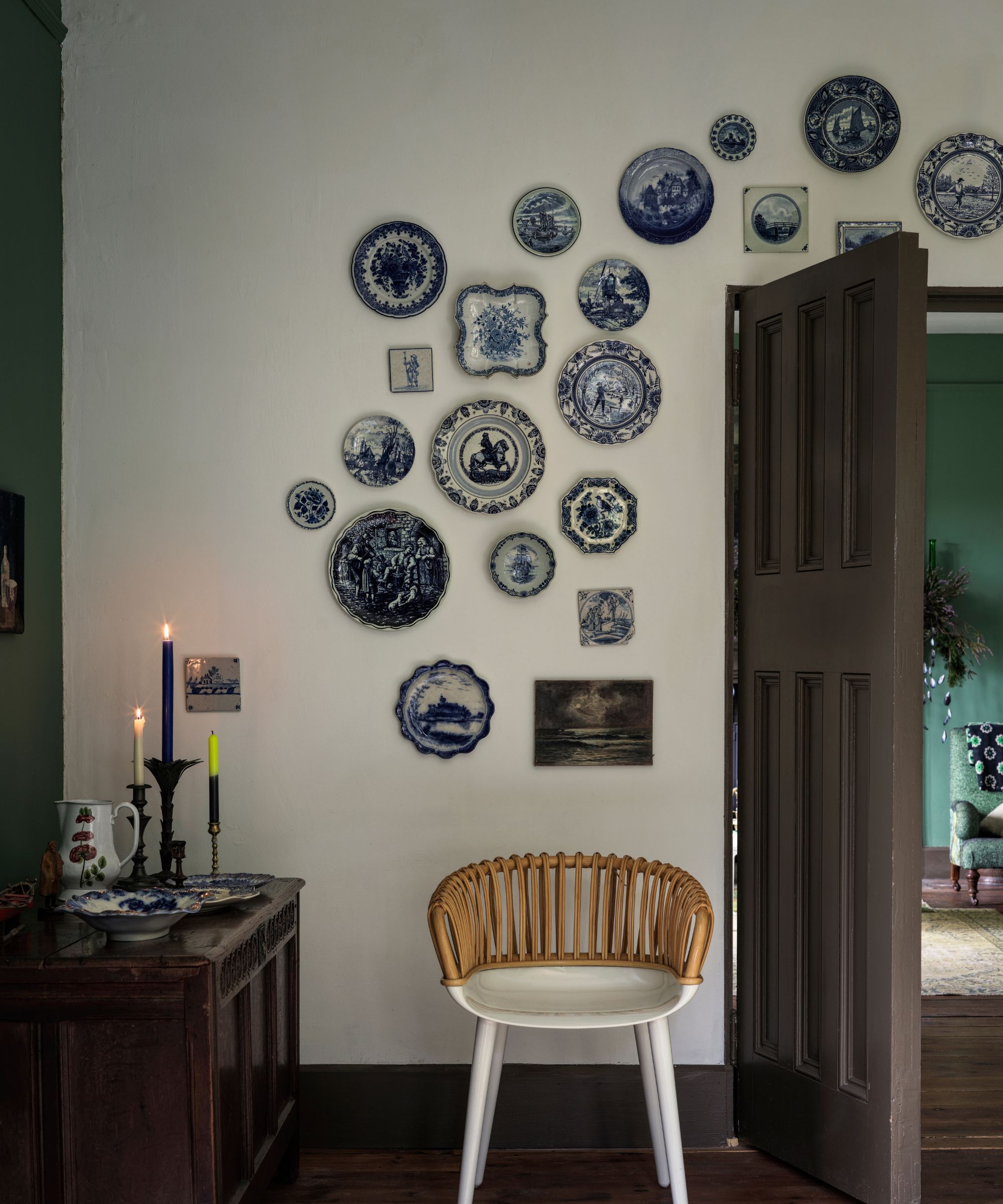 a wall with vintage plates hanging on it, a chair below, and a credenza to the left