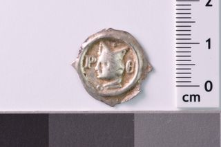 Medieval coin from Glottertal on a gray background. A man's face in profile is on the coin.