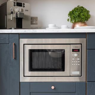 silver microwave set in kitchen cupboards under counter top