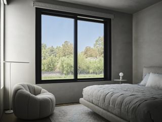 A bedroom with light gray walls and light gray bedding