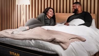 A man and woman laugh and talk while lying on the Titan Plus Elite mattress 