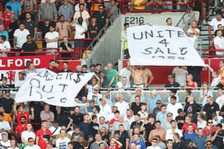 Manchester United fans hold up banners in protest against the club owners, The Glazers during the Premier League match between Brentford FC and Manchester United at Brentford Community Stadium on August 13, 2022 in Brentford, United Kingdom.