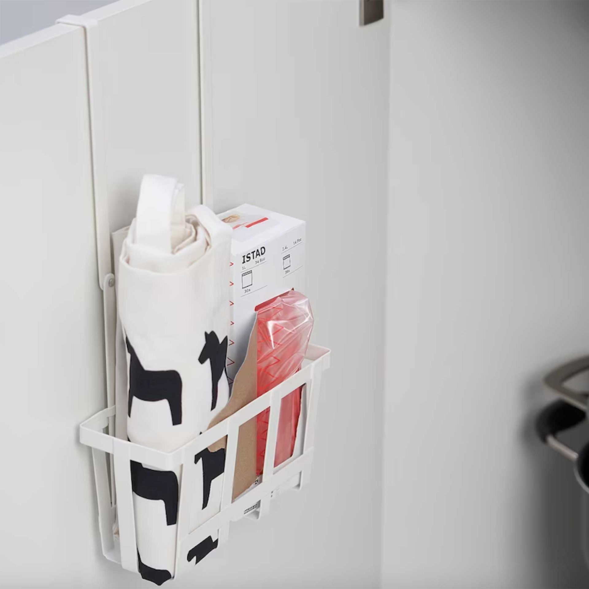 White plastic basket over a white cabinet door to organise under a kitchen sink