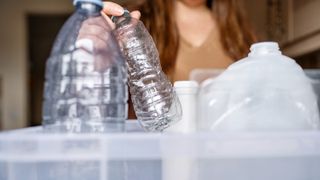 hand placing empty plastic water bottles into tub