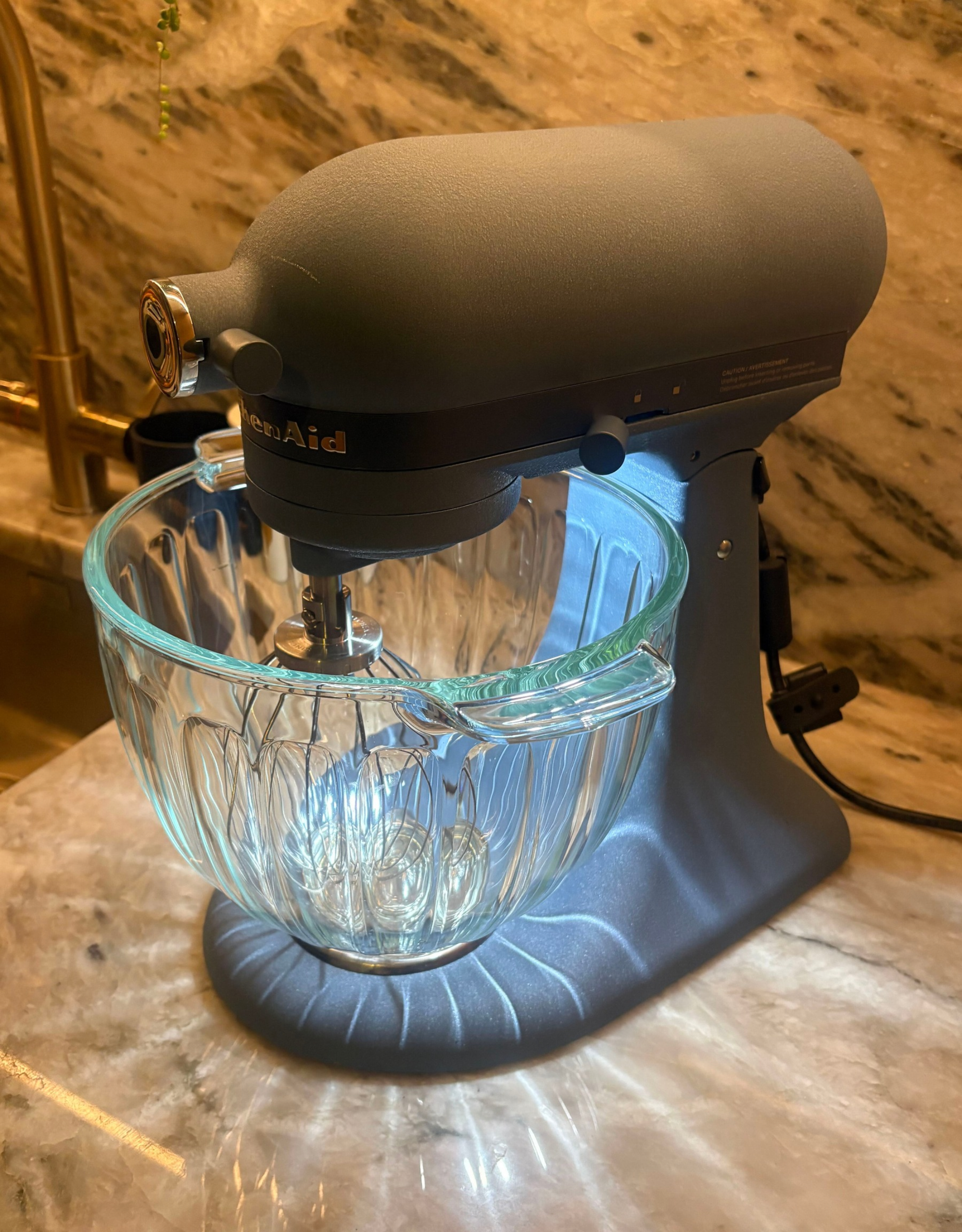 the kitchenaid luminaire casting patterns of light through the fluted glass bowl on stone counters