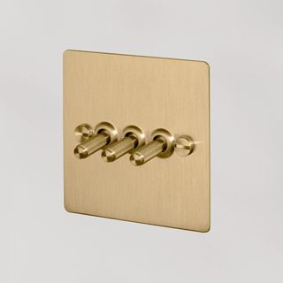 A brushed brass toggle light switch with toggles 